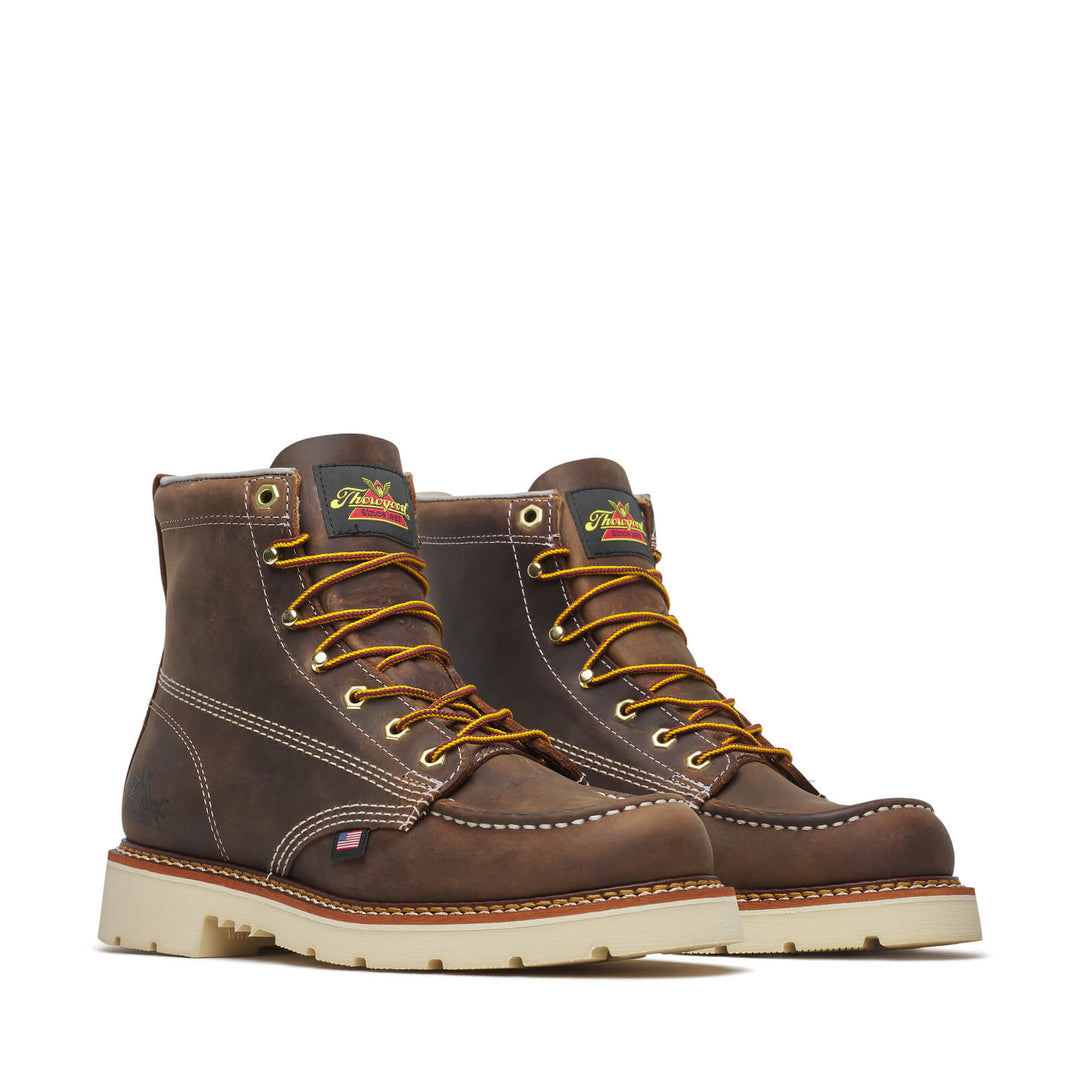 Pair of brown work boots with yellow laces on a white background