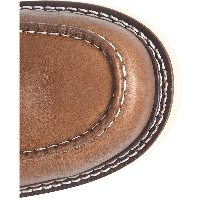 A close up view of the toe of a tan boot with a white background. 